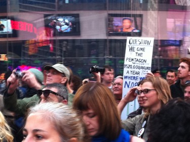 Manifestantes pasando por el índice de Nasdaq en Times Square. Foto de Robert Valencia para Global Voices, 2011