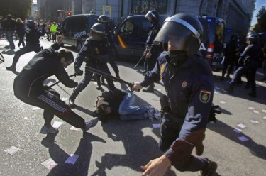 Madrid: polícia anti-motim rodeia um jovem caído no chão. Fotografia da página de Facebook «AntenapezTV»