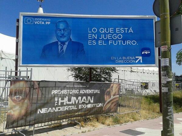 Valla publicitaria del PP junto al anuncio de una exposición de hombres de neandertal. Foto subida a Twitter por Patricia F de Lis