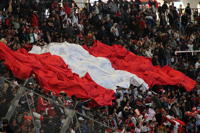 The Peruvian flag in the crowd during a football match. Image on Flickr by user <a href="https://www.flickr.com/photos/teruhn/8490288381">Teru Kaleru</a>. CC BY-NC-ND 2.0.