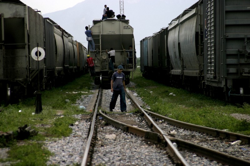 Central American migrants hop a freight train in Ciudad Ixtepec, Mexico on July 15, 2008. The trains are nicknamed "La Bestia" - the Beast - and will take them on a perilous journey 1,500 miles north to the U.S.-Mexican border. Canada's SAWP program flies workers in on a plane. Photo by Peter Haden.